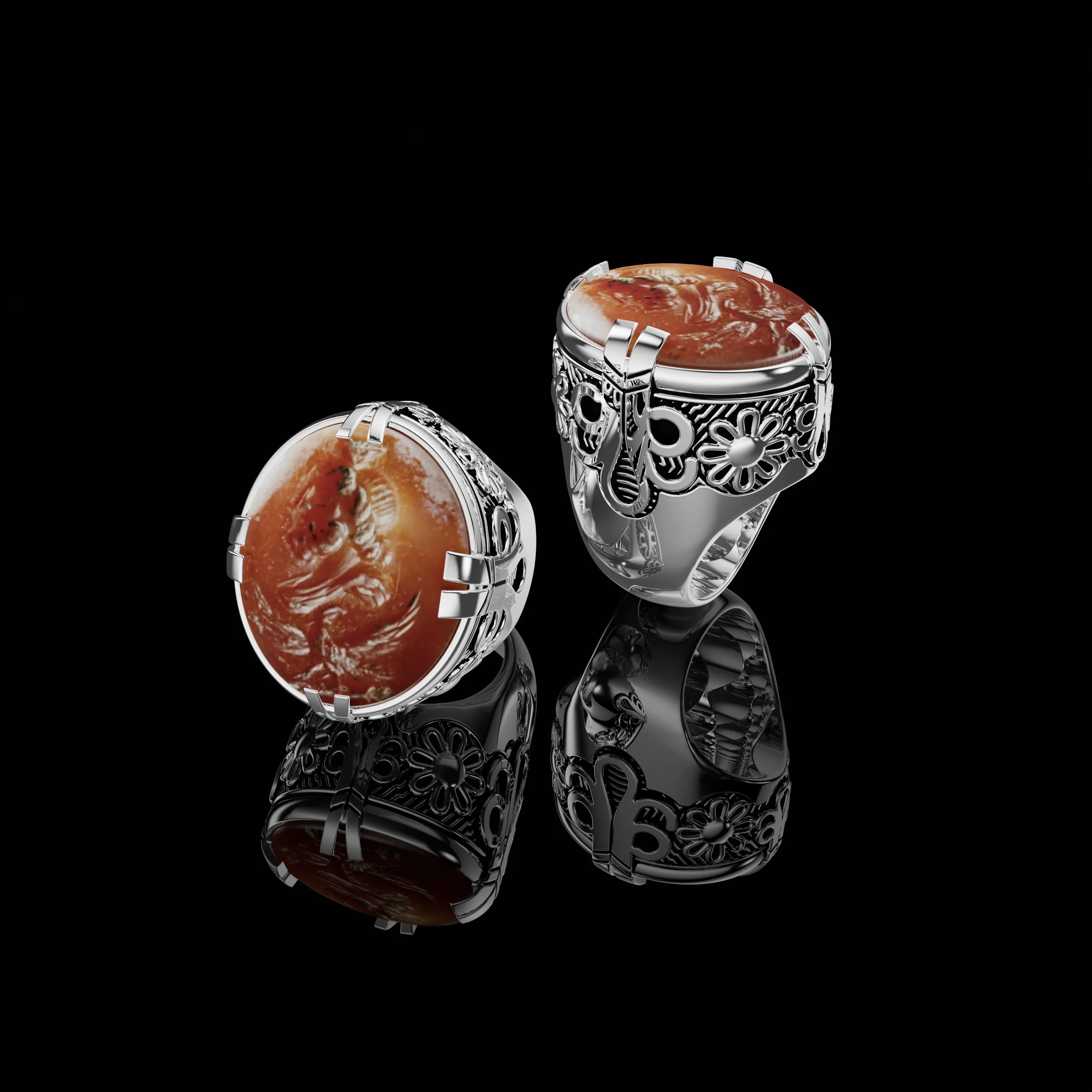Sculptural silver rings with warm-toned oval stones and detailed settings on a black background